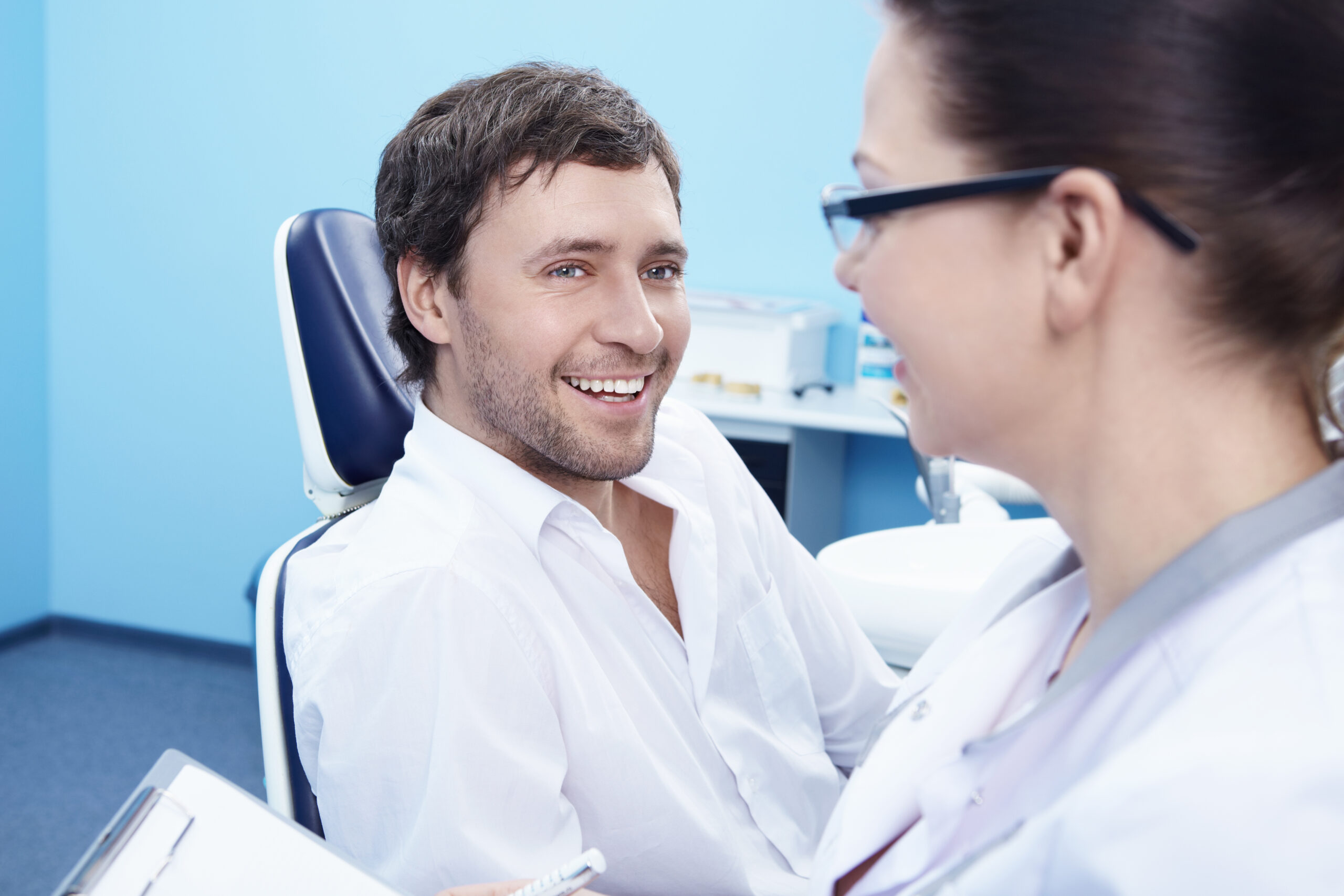 Male patient smiling during a cosmetic dentistry consultation in a dental office.
