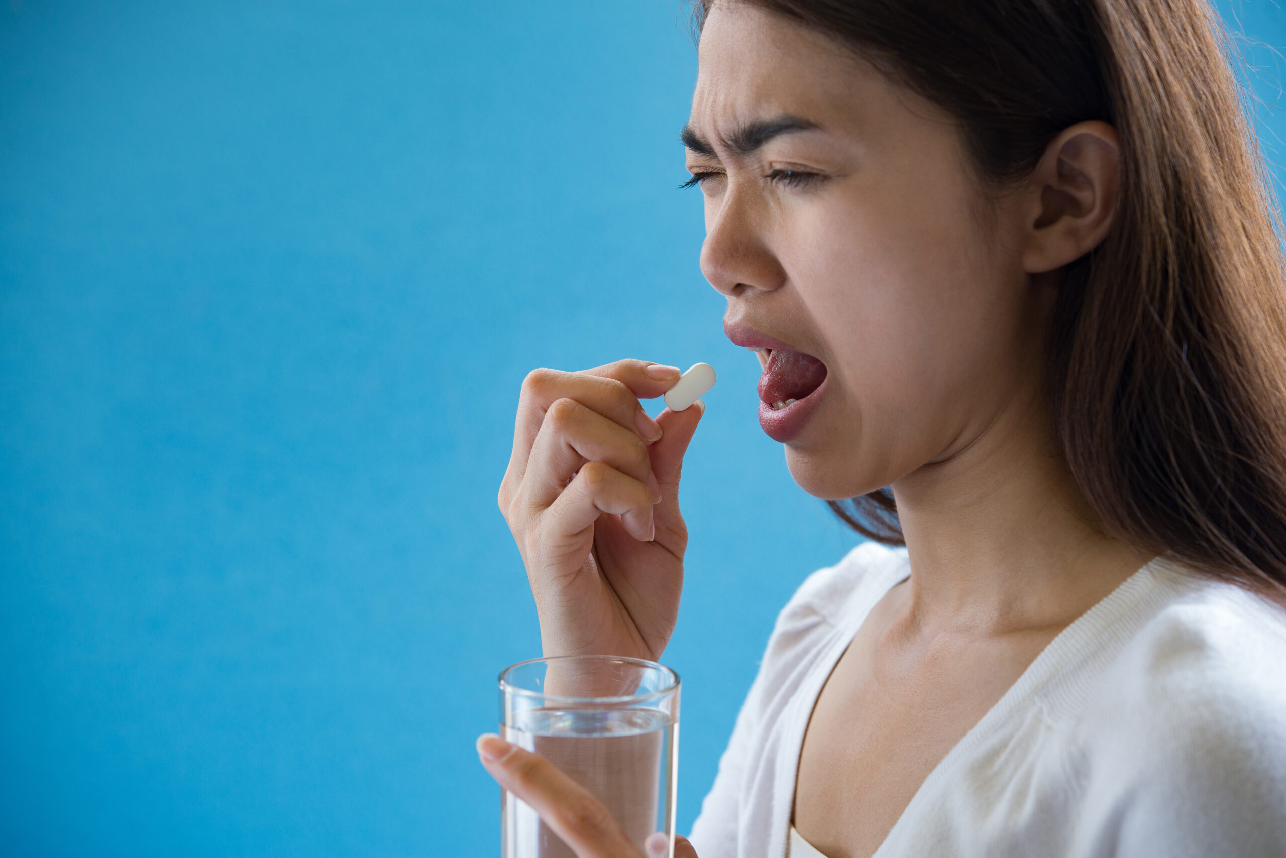 Close-up of a glass of water next to prescription medication bottles, symbolizing solutions for dry mouth caused by medications.